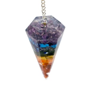 May include: A seven chakra crystal pendulum with a silver chain. The pendulum is made of clear resin with embedded crystals in each chakra color: purple, indigo, blue, green, yellow, orange, and red.
