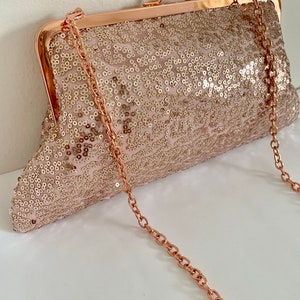 May include: A rose gold sequined clutch with a rose gold chain strap.