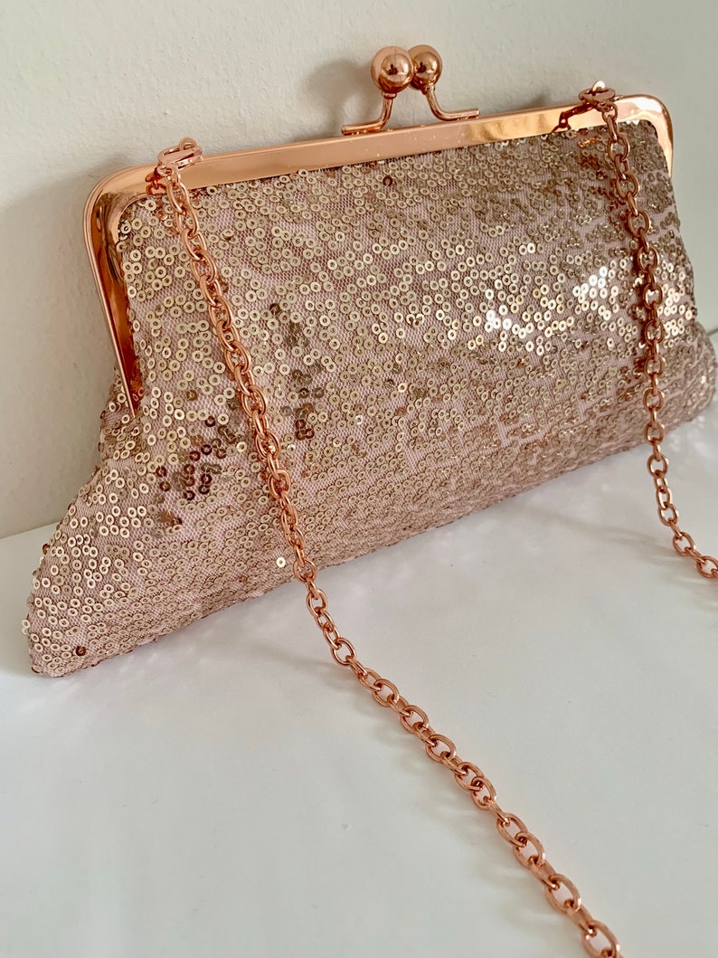 May include: A rose gold sequined clutch with a rose gold chain strap.