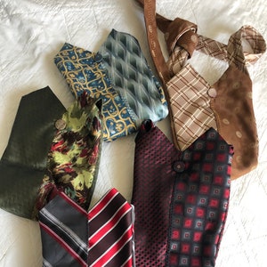 May include: Six small bags made from repurposed neckties. The bags are in various colors and patterns, including green, brown, red, blue, and gray. Some of the bags have buttons.