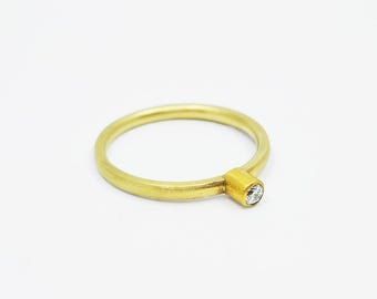 May include: A simple gold band ring with a single, small, clear diamond set on the side.