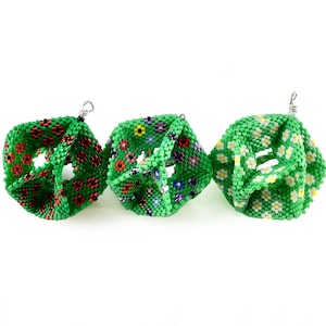 May include: Three green beaded ornaments with floral patterns. Each ornament has a different floral design, including red and black flowers, multi-colored flowers, and white flowers.