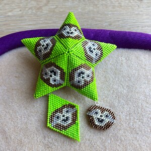 May include: A green star-shaped ornament with a beaded design and a white and brown pattern. The ornament is accompanied by two smaller matching pieces, one diamond-shaped and one round.