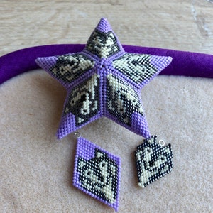 May include: A purple star-shaped beaded ornament with black and white geometric patterns. Two smaller matching purple beaded ornaments are also included.