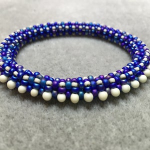 May include: A blue and white beaded bracelet with a spiral design. The bracelet is made with small, round beads in shades of blue and white.