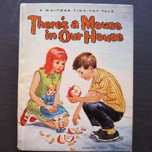 May include: Vintage children's book cover titled "There's a Mouse in Our House." The cover art depicts a young girl in a green dress and a boy in a striped shirt examining an apple. The book is a Whitman Tiny-Tot Tale.