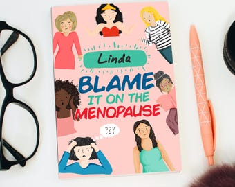 May include: A pink and green illustrated book cover with the title "Blame It On The Menopause" and the name "Linda" in a green oval. The cover features several cartoon women with different expressions and hairstyles.