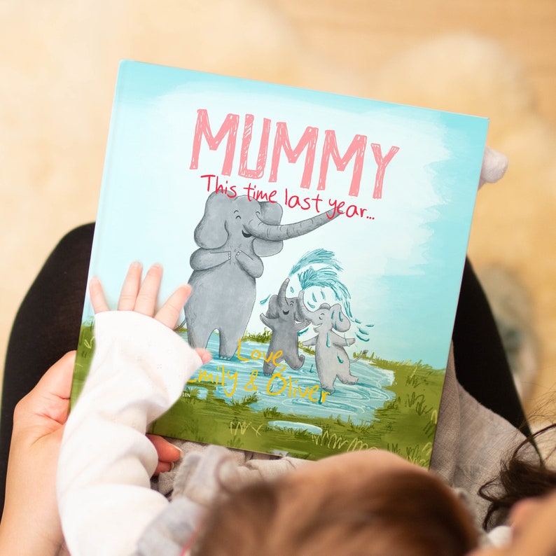 May include: A blue and green illustrated book with the title "Mummy" in pink lettering. The book says "This time last year..." and features a mother elephant and two baby elephants playing in a puddle.