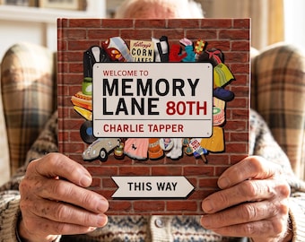 May include: A hardback book with a red brick wall background. The cover features a white sign reading WELCOME TO MEMORY LANE 80TH CHARLIE TAPPER, surrounded by various vintage illustrations. A white arrow sign below reads THIS WAY.