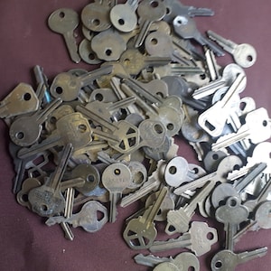 Könnte beinhalten: Ein großer Haufen Vintage-Schlüssel, meist silberfarben, mit einigen Messingakzenten. Die Schlüssel sind in einem zufälligen Muster angeordnet, wobei sich einige Schlüssel überlappen. Die Schlüssel sind alle in verschiedenen Formen und Größen.