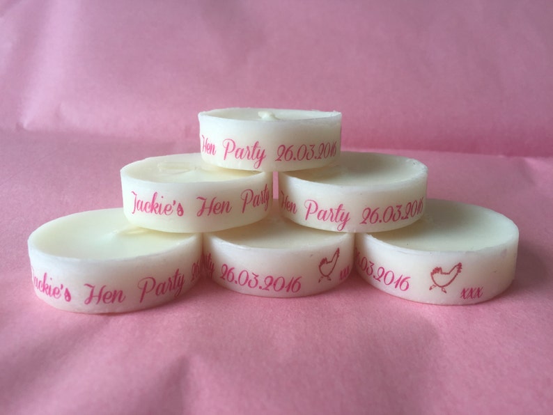 K&ouml;nnte beinhalten: Ein Stapel aus sechs wei&szlig;en Teelichtern mit rosa Beschriftung. Die Kerzen sind mit dem Text "Jackie's Hen Party" und dem Datum "26.03.2016" verziert.
