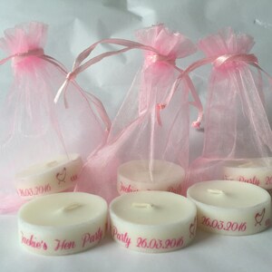 K&ouml;nnte beinhalten: Sechs kleine wei&szlig;e Kerzen mit rosa Beschriftung. Die Kerzen befinden sich in rosa Organzas&auml;ckchen. Der Text auf den Kerzen lautet "Jackie's Hen Party 26.03.2016".