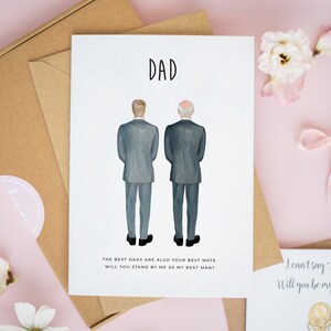 May include: A greeting card featuring the word DAD at the top and an illustration of two men in grey suits standing with their backs to the viewer. Below the figures, the text reads: THE BEST DADS ARE ALSO YOUR BEST MATE. WILL YOU STAND BY ME AS MY BEST MAN?