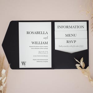 Könnte beinhalten: Schwarze Hochzeitseinladung mit weißem Text. Die Einladung enthält die Namen Rosabella und William, das Datum 180323 und Veranstaltungsdetails. Zusätzliche Karten enthalten Informationen, Menü und RSVP-Details. Die RSVP-Karte bittet um Rücksendung bis Dezember 2022.