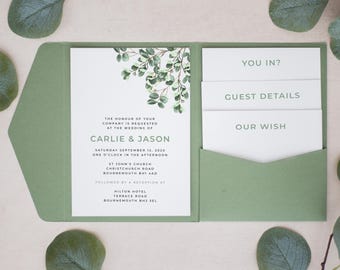 May include: A sage green wedding invitation folder containing a white card with eucalyptus illustrations and text for Carlie & Jason, plus three smaller white cards labeled You In?, Guest Details, and Our Wish, all arranged on a light surface.