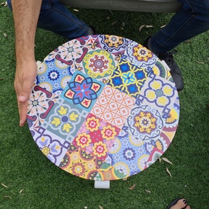 May include: A round, colorful table top with a mosaic tile design. The table top is made of wood and has a white metal base.