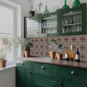 May include: A kitchen with green cabinets and a backsplash of colorful patterned tiles. There are plants on the counter and bottles on the shelves.