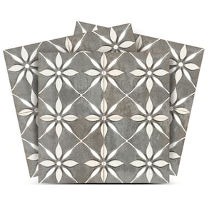 May include: Three gray ceramic floor tiles with a white floral pattern. The tiles have a distressed look and are arranged in a stack.