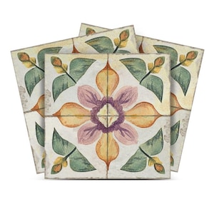 Pode incluir: Três azulejos quadrados de cerâmica com um design floral. Os azulejos apresentam uma flor central com pétalas amarelas, laranja e rosa, rodeada de folhas verdes. O fundo dos azulejos é de cor bege claro.