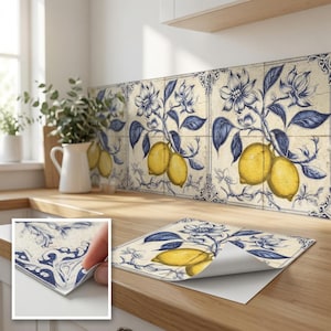 Può includere: Un set di piastrelle quadrate da parete con un'illustrazione botanica di limoni gialli e fiori blu su sfondo crema. Le piastrelle presentano un bordo blu decorativo e sono mostrate come fogli adesivi con retro staccabile per l'applicazione.