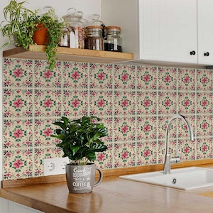 May include: Pink and green floral tile stickers with a white background. The tiles are arranged in a grid pattern and cover a kitchen backsplash. A coffee mug with the text "Good Morning starts with Coffee" is sitting on a countertop in front of the tiles.