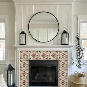 May include: A white fireplace mantel with a black mirror and two black lanterns. The fireplace has a black surround and a black firebox. The fireplace is decorated with pink and green floral tile.