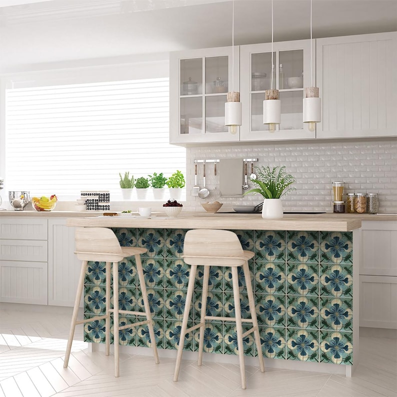 Puede incluir: Una isla de cocina con dos taburetes de bar, que presenta un salpicadero de azulejos con patrones azules y verdes. La isla tiene una encimera de madera clara y armarios blancos.
