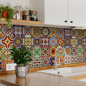 May include: A kitchen backsplash featuring colourful patterned tiles in shades of red, blue, yellow, green, and white. A white porcelain sink with a chrome tap is in the lower right corner. A small potted plant sits on the counter below the backsplash.