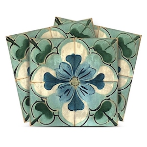 Op de afbeelding: Set van drie blauwe en groene keramische tegels met een bloemenmotief. De tegels hebben een grote blauwe bloem met witte accenten en groene bladeren.