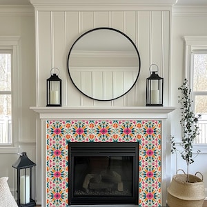 May include: A white fireplace mantel with a black mirror above it. The fireplace has a black surround and a black firebox. The mantel is decorated with a patterned tile surround in shades of pink, orange, teal, and white.