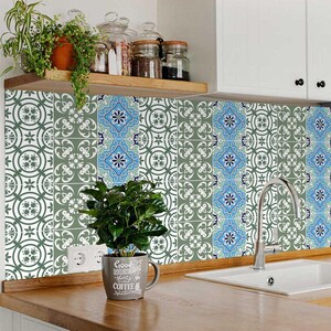 May include: A kitchen backsplash with a blue and green patterned tile design. The tile design features a repeating pattern of geometric shapes and floral motifs. The backsplash is installed above a kitchen sink and countertop.