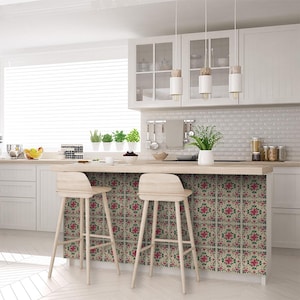 May include: A kitchen island with a white countertop and two wooden bar stools. The backsplash is covered in decorative tile with a floral pattern in shades of pink, green, and cream.