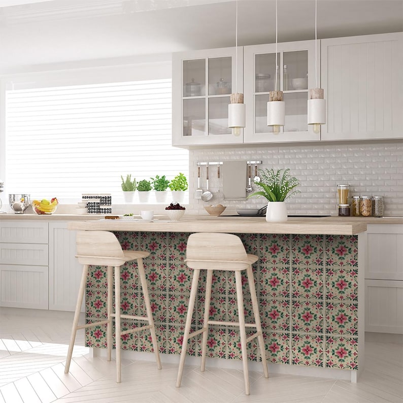 May include: A kitchen island with a white countertop and two wooden bar stools. The backsplash is covered in decorative tile with a floral pattern in shades of pink, green, and cream.