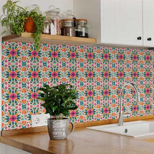 May include: A kitchen backsplash with colorful floral tile stickers. The tiles are a cream color with pink, orange, and teal accents. A coffee mug with the text "Good Morning starts with Coffee" is sitting on the counter in front of the backsplash.