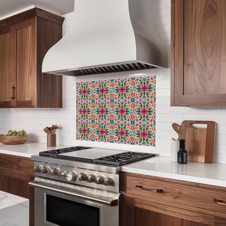 May include: A stainless steel range hood with a white canopy over a kitchen stove with a patterned backsplash. The backsplash is a repeating pattern of colorful flowers and geometric shapes.