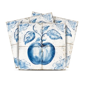 Op de afbeelding: Drie blauwe en witte keramische tegels met een blauw appelontwerp. De appel zit aan een wijnstok met bladeren. De tegels hebben een verweerde uitstraling.