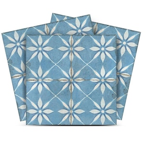 Könnte beinhalten: Drei blaue Keramikfliesen mit einem weißen Blumenmuster. Die Fliesen haben einen abgenutzten Look, der ihnen ein Vintage-Feeling verleiht.
