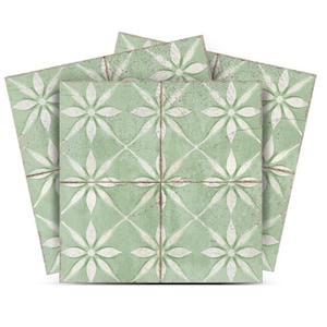 May include: Three green ceramic tiles with a white floral pattern. The tiles have a distressed look, giving them a vintage feel.
