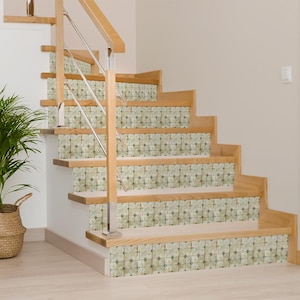 May include: Wooden staircase with decorative tile risers. The steps are made of light-colored wood, and the risers feature a repeating floral pattern in shades of green and beige. A stainless steel railing provides support.