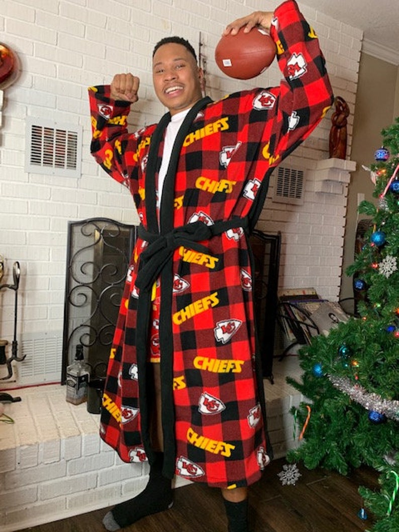 May include: A red and black flannel robe with the word "Chiefs" printed in yellow on it. The robe is being worn by a person holding a football.