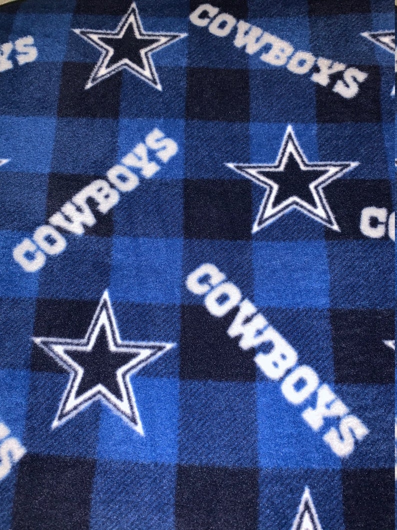 May include: Blue and black checked fleece blanket with a white "Cowboys" logo and a white five-pointed star with a blue centre.