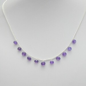 May include: A silver chain necklace with small purple amethyst beads dangling from it.