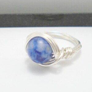May include: A silver wire wrapped ring with a blue and white agate stone.