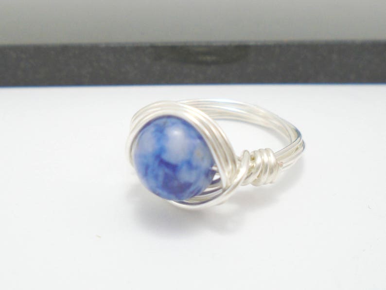 May include: A silver wire wrapped ring with a blue and white agate stone.