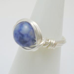 May include: A silver wire wrapped ring with a blue and white stone.
