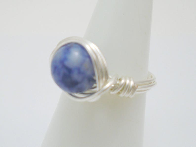 May include: A silver wire wrapped ring with a blue and white stone.