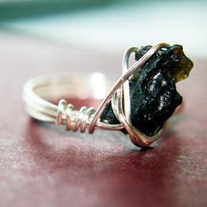 May include: A silver wire wrapped ring with a black and green gemstone.
