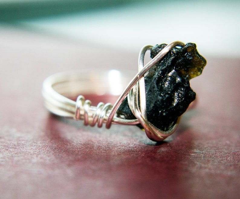 May include: A silver wire wrapped ring with a black and green gemstone.