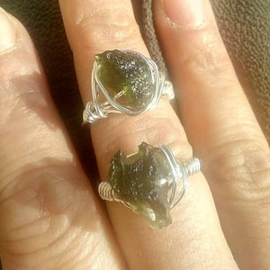 May include: Two rings with green, iridescent, rough, natural stones wrapped in silver wire.