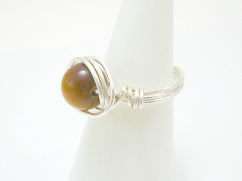 May include: A silver wire wrapped ring with a brown tiger's eye stone.